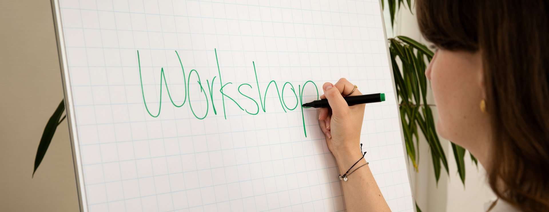 Frau schreibt an ein Flipshart Board das Wort "Workshop".
