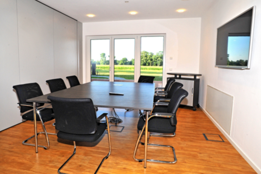 Ein kleiner Besprechungsraum mit einem Tisch und Stühlen.