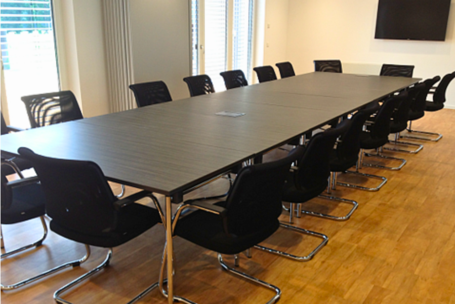 Ein großer Besprechungsraum mit einem langen Tisch und vielen Stühlen.