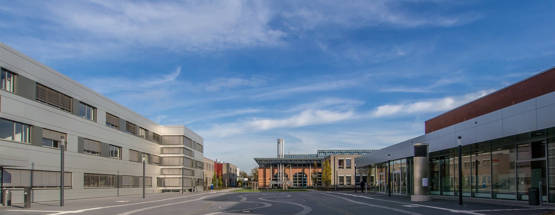 Ein moderner Hochschulcampus vor einem blauen Himmel.