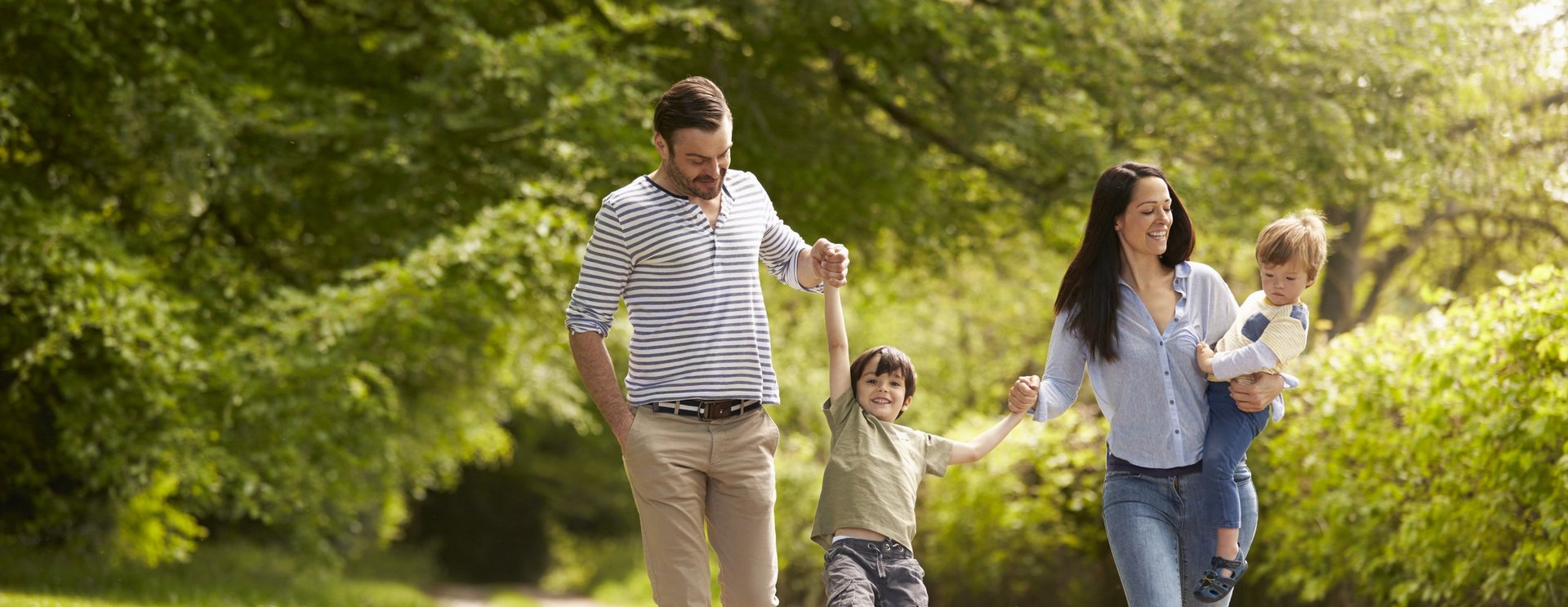 Eine Familie mit zwei Kindern läuft durch einen Park