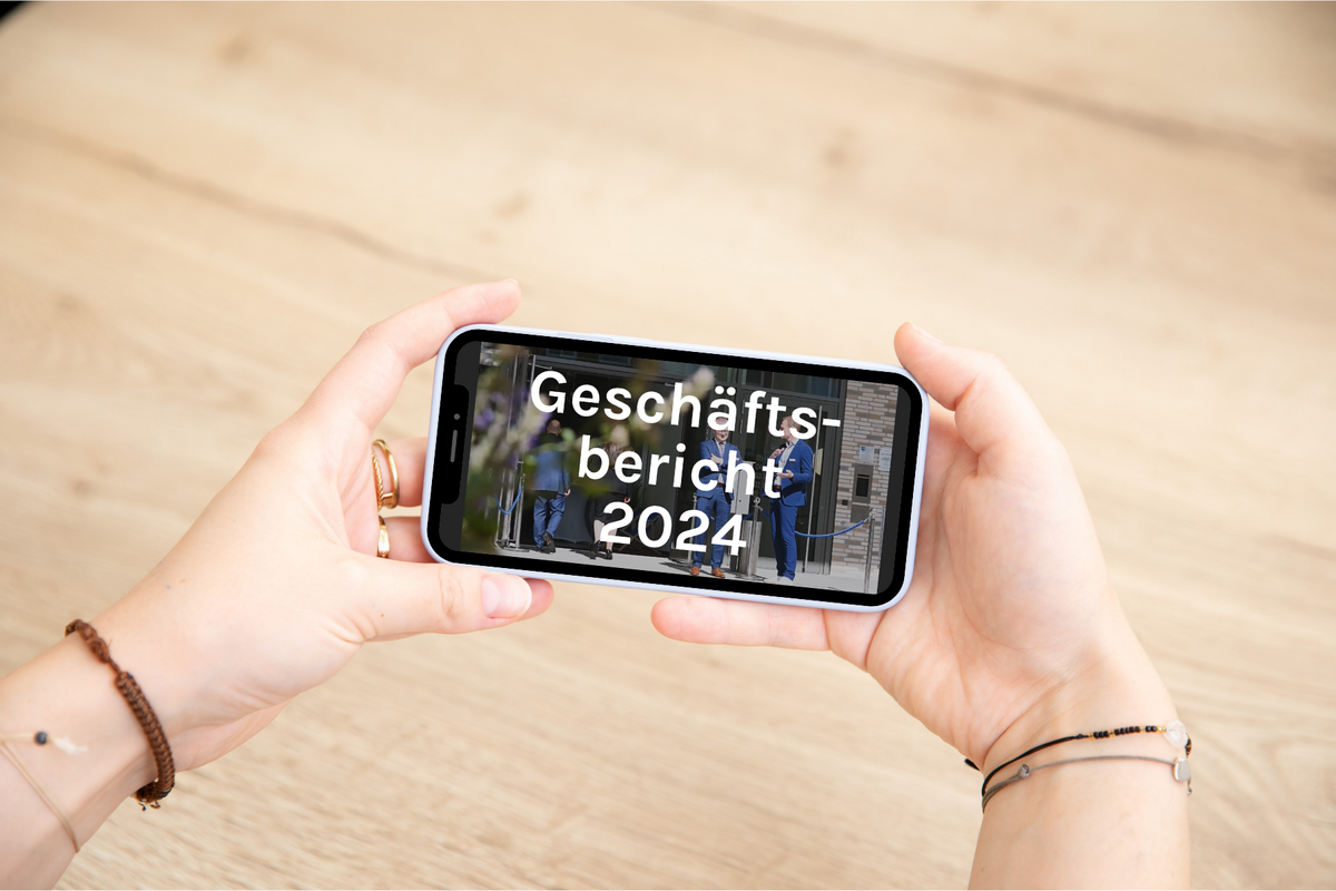 Zwei Hände halten ein Smartphone, auf dessen Bildschirm der Text ‚Geschäftsbericht 2024‘ angezeigt wird.Zwei Hände halten ein Smartphone, auf dessen Bildschirm der Text "Geschäftsbericht 2024" angezeigt wird.